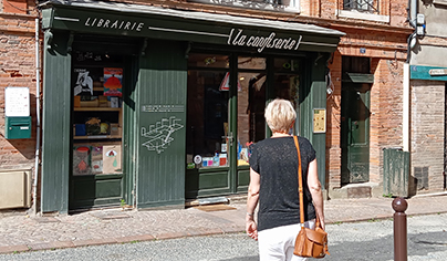 Photo : dans la rue, une personne de dos s'approche à l'entrée de la librairie