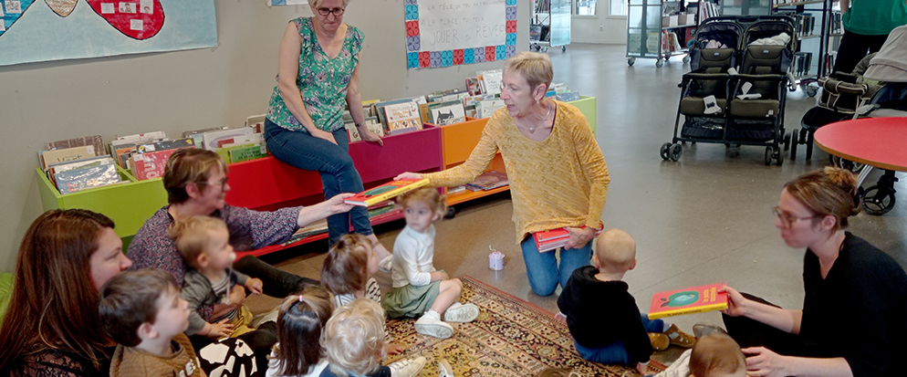 Animatrices et enfants assis sur un tapis à la médiathèque